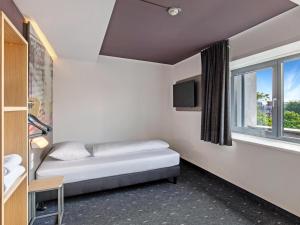 a small room with a bed and a window at B&B Hotel Hamburg-Airport in Hamburg