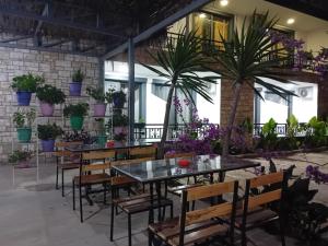 a restaurant with tables and chairs and potted plants at Villa Allkushi in Sarandë