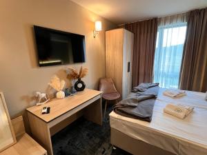 a hotel room with a bed and a desk and a television at Pino - Villa, Casa, Cucina е Terrazza in Albena