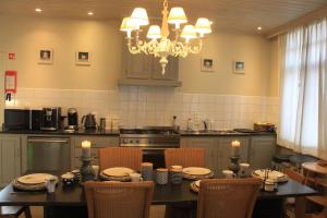 a kitchen with a table with chairs and a chandelier at Gastenverblijf Huize Pervijze in Pervijze