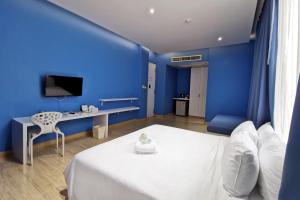 a blue room with a bed and a desk at Beat Hotel Bangkok in Bangkok