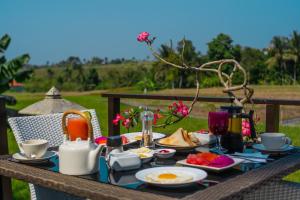 a table with a breakfast of eggs and fruit on it at Balam Bali Villa in Mengwi