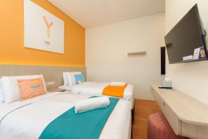 a room with two beds and a flat screen tv at Sans Hotel Tajur Bogor in Bantarkamang