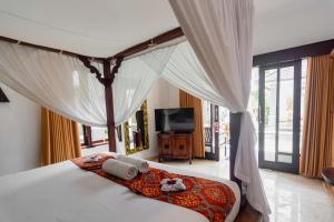 a bedroom with a canopy bed with a television at Balam Bali Villa in Mengwi