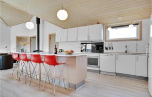 a kitchen with white cabinets and red bar stools at Lovely Home In Løkken With Wifi in Løkken