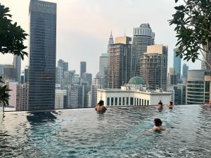 吉隆坡Axon Residence Suites KL的一群人在一座城市天际线的无边泳池游泳