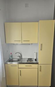 a small kitchen with yellow cabinets and a sink at Apartment Grubelić in Tribunj