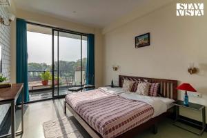 a bedroom with a bed and a balcony at Serenity By The Ganges with Alfresco Dining at Varanasi by StayVista in Varanasi +22 photos