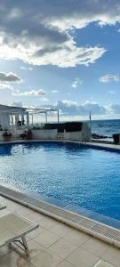 a large swimming pool with the ocean in the background at Fracco's House S. Marinella fronte mare 36' di treno da Roma in Santa Marinella