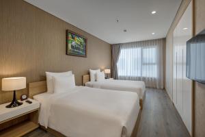 a hotel room with two beds and a television at Abogo Apartment FHome Riverside in Da Nang +15 photos