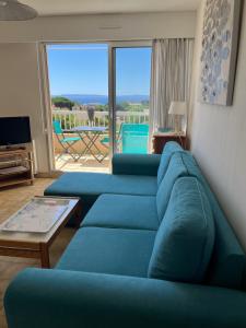 ル・ラヴァンドゥーにあるLe Lavandou St Clairのリビングルーム(青いソファ2台、バルコニー付)