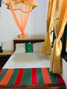 1 dormitorio con 1 cama con cortinas en Gami Gedara Homestay, en Polonnaruwa