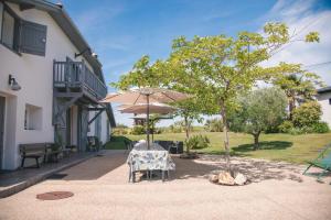 a table with an umbrella next to a building at Villa Bet Loc 14 personnes in Saubrigues
