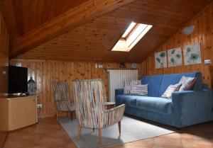 a living room with a blue couch and two chairs at Casa Barbóla in Sondalo