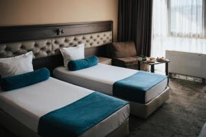 a hotel room with two beds and a chair at Business Hotel Plovdiv - Central Location in Plovdiv