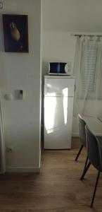 a white refrigerator in a room with a table and chairs at Apartment Grubelić in Tribunj +2 photos