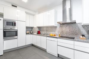 a white kitchen with white cabinets and appliances at The Corner Apartments by Aspasios in Barcelona