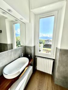 a bathroom with a large white tub and two windows at Lilly del Lago Maggiore in Castelveccana +23 photos