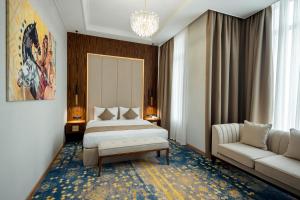 a bedroom with a king sized bed and a couch at Qazaq Hotel Premium in Shymkent
