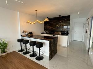 eine Küche mit einer Bar mit schwarzen Stühlen in der Unterkunft Luxury apartament Luz Mar in playa de los Locos in Torrevieja