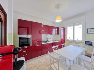 a kitchen with red cabinets and a white table at Ampio appartamento con vista in Varazze