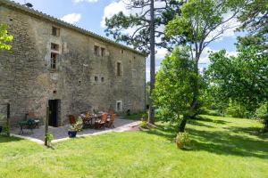 a stone building with a table and chairs in a yard at Maison d'Hôtes Mas de la Chadenede in Lagorce