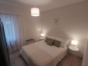 a white bedroom with a bed and two lamps at Casa del barbiere in Dogliani