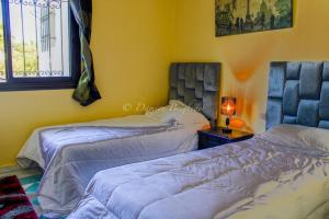 a bedroom with two beds and a lamp on a table at Charmant appartement au bord de mer in El Jadida
