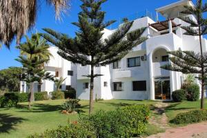 a large white building with trees in front of it at Charmant appartement au bord de mer in El Jadida