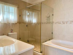 a bathroom with a shower and a tub and a sink at Beverley Hills Studio in Ballito +9 photos