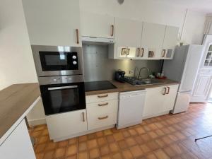 a kitchen with white cabinets and black appliances at Charmante Maison La Source 2p 50m2 Quartier Paul Bert in Tours +8 photos