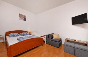 ein Schlafzimmer mit einem Bett und einem Stuhl und einem Fernseher in der Unterkunft Apartments Dulabic in Poreč