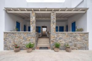 a stone building with stairs and potted plants at Dorkas Luxury Rooms&Apartments in Livadakia