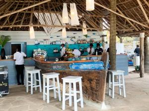 a restaurant with a bar with white stools at Vipingo Ridge limited in Kilifi