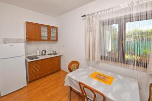 eine Küche mit einem Tisch und einem weißen Kühlschrank in der Unterkunft Apartments Dulabic in Poreč