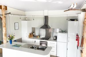 a white kitchen with a sink and a refrigerator at Larus Waterfront Cottage in White Beach