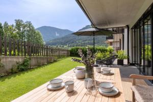 een houten tafel met borden en glazen en een paraplu bij Apartment EMILY Brixental in Brixen im Thale +14 foto's