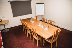 a conference room with a large wooden table and chairs at OYO The Red Lion Hotel in Luton