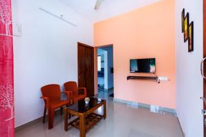 a living room with a table and chairs and a tv at Galaxy Homestays in Malpe