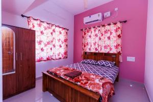 a bedroom with a bed with pink walls at Galaxy Homestays in Malpe