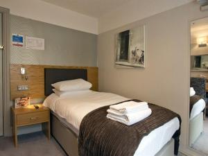 a bedroom with a bed with a pile of towels at OYO The Red Lion Hotel in Luton