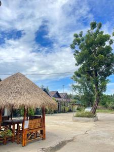 a straw umbrella and a table and a tree at Pich Mean Bungalow in Sihanoukville