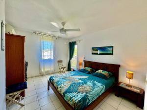 a bedroom with a bed with a blue comforter at Grand appartement confortable 2 chambres proche marina in Saint-François