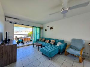 a living room with a blue couch and a television at Grand appartement confortable 2 chambres proche marina in Saint-François