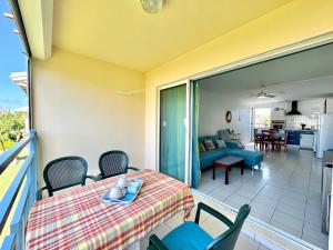 a balcony with a table and chairs and a living room at Grand appartement confortable 2 chambres proche marina in Saint-François +12 photos