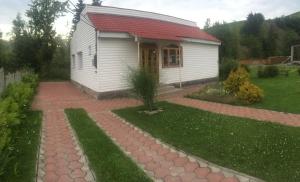 uma pequena casa branca com um telhado vermelho em Merydian em Yasinia