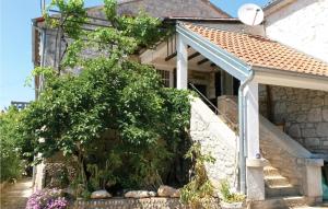 a stone house with a white porch and a tree at Two-Bedroom Apartment In Vrsar in Vrsar