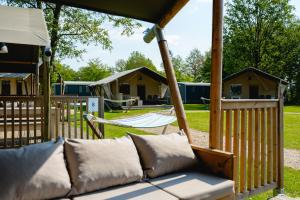 a porch with a couch and a hammock at Glamping Winterswijk in Miste