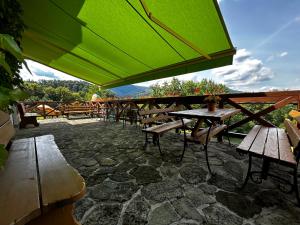 a group of tables and benches with a green umbrella at Mileżówka - Noclegi&SPA in Ustroń