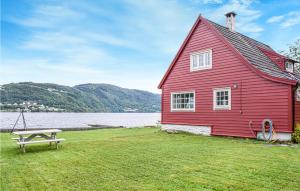 a red house with a picnic table in front of a lake at Lovely Home In Garnes With Wifi in Garnes